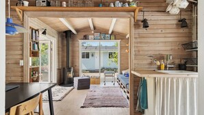 Un accogliente interno di una baita con arredamento in legno, una zona pranzo, una cucina con lavandino e un caminetto.