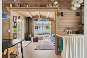 Ein gemütliches Blockhaus-Interieur mit Holzvertäfelung, einem Essbereich, einer Küche mit Spüle und einem Kamin.