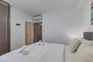 Ein Hotelzimmer mit Bett, Kissen, einer Tür und einer Klimaanlage.
