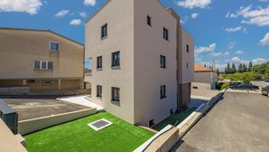 A multi-story residential building with a flat roof, multiple windows, and a parking area. - Zadar 3BR Penthouse /w Rooftop Terrace & Jacuzzi, Zadar, Croatia (Zadar)