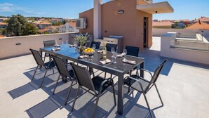 A rooftop terrace with a glass table set for dining, surrounded by chairs. - Zadar 3BR Penthouse /w Rooftop Terrace & Jacuzzi, Zadar, Croatia (Zadar)