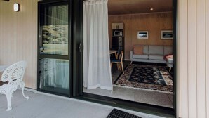 Ein modernes Interieur mit einer Schiebeglastür, die zu einem Wohnbereich mit Sofa, Esstisch und Mikrowelle führt.