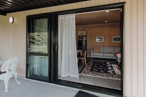 Ein modernes Interieur mit einer Schiebeglastür, die zu einem Wohnbereich mit Sofa, Esstisch und Mikrowelle führt.