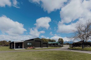 A modern building with a covered outdoor area, large garage doors, and a paved driveway. - Tremorne Stay: Couples Retreat in Taranaki (Inglewood)