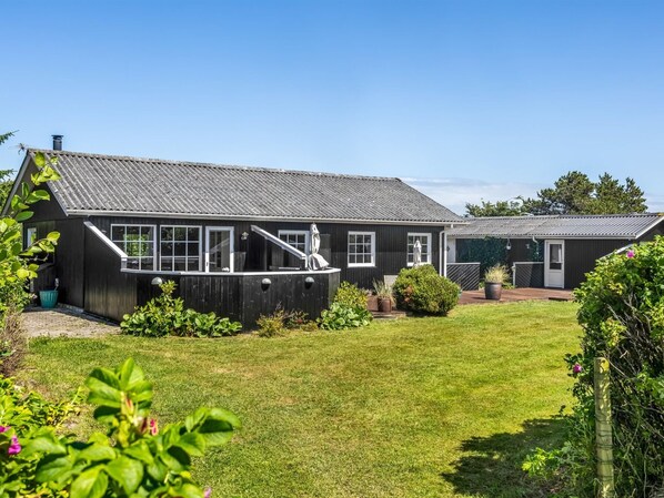 Une maison en bois à deux étages, avec un toit en pente, un porche à l’avant et une pelouse bien entretenue.
