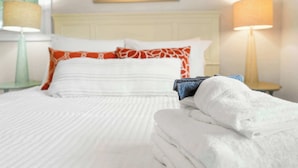 A neatly made bed with white linens and a pillow with a red and white pattern. - Walk to Surfside Beach Access, Golf Cart Add On (St. Augustine)