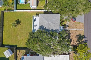 Ein Wohngebiet mit einem großen Baum, einem Haus mit Satteldach und einem geparkten Fahrzeug.