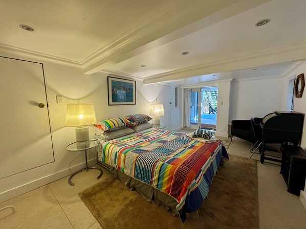 A hotel room with a bed, two bedside lamps, a desk with a chair, and a view of the outdoors.