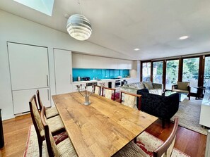 A modern kitchen with white cabinets, a blue backsplash, and a dining area with a wooden table and chairs.