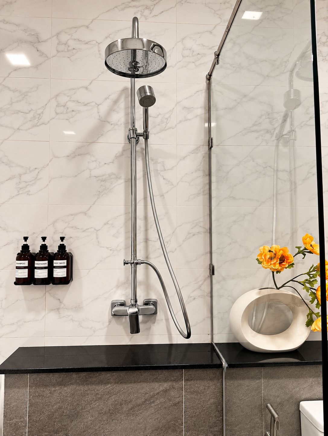A modern bathroom with a shower, a toilet, and a sink.