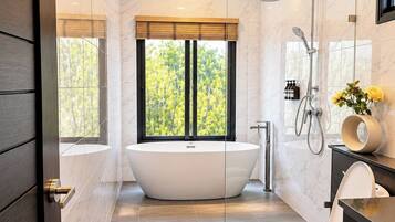 Een moderne badkamer met een vrijstaand bad, een douche met glazen wanden en een toilet.