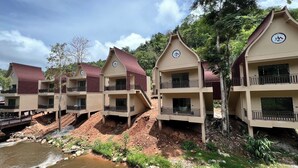 A row of multi-story buildings with balconies, situated by a river. - T-Valley Maekampong  (Mae On)