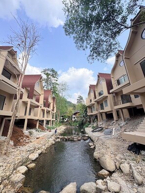 A residential complex with multiple-story buildings, a central water feature, and surrounding greenery. - T-Valley Maekampong  (Mae On)