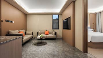 A modern hotel room with a sofa, a coffee table, a bed, and a TV.