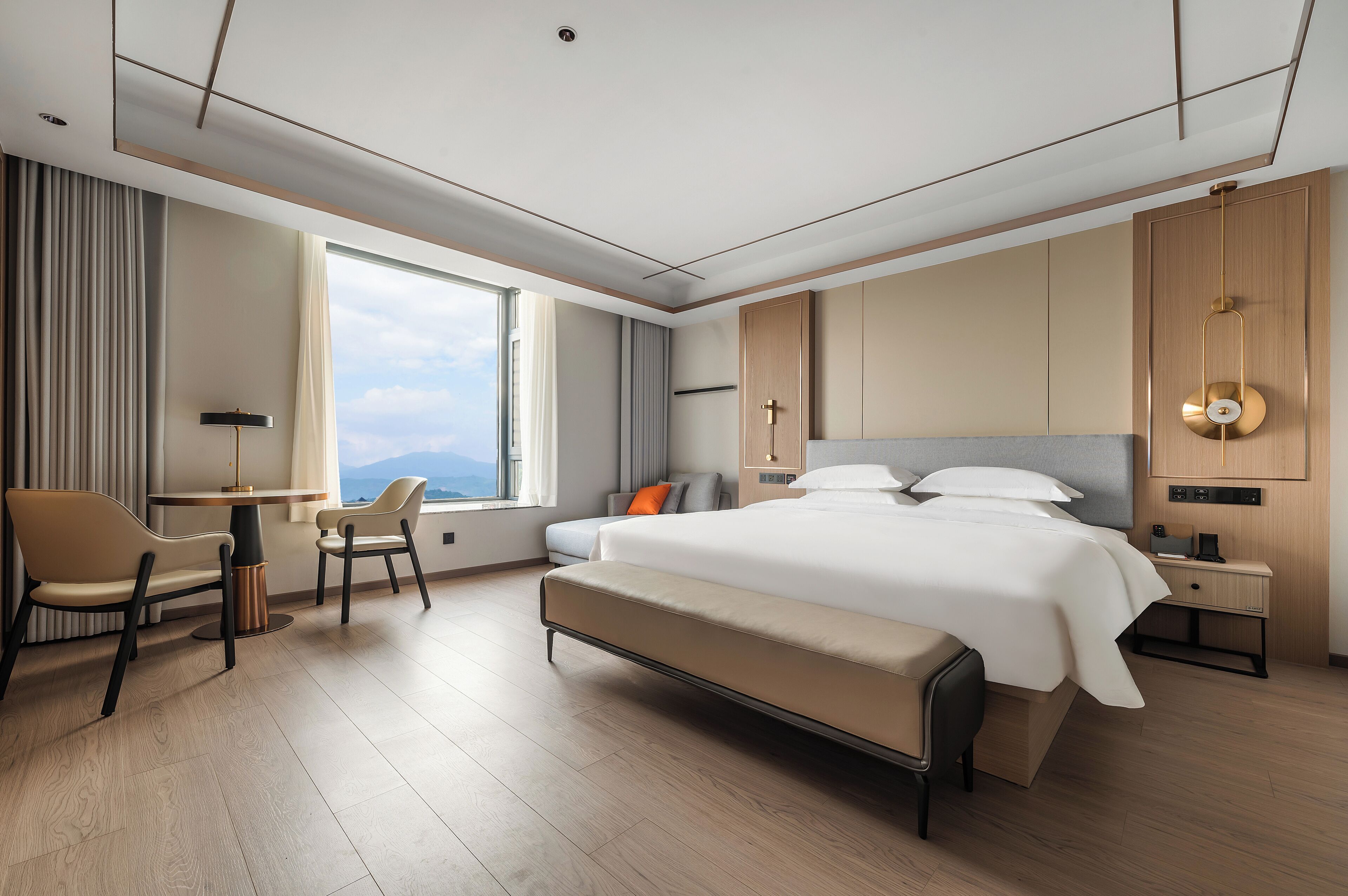 Habitación de hotel moderna con una cama grande, un escritorio y vistas a las montañas.