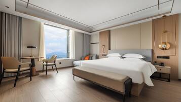 Habitación de hotel moderna con una cama grande, un escritorio y vistas a las montañas.