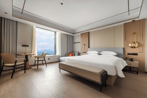 Habitación de hotel moderna con una cama grande, un escritorio y vistas a las montañas.