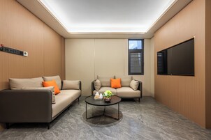 Una sala de estar moderna con un sofá, un sillón, una mesa de centro y un televisor de pantalla plana montado en la pared.