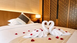 Una habitación de hotel con una cama bien hecha, un cojín decorativo, una pared con patrones geométricos y una lámpara de noche.
