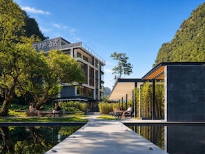 A modern hotel with a pool, outdoor seating, and a view of the surrounding greenery. - The Floral Dreamscape Retreat -Yulong Romance Park Branch-Tickets Reservation & Day Tour Arrangement (Guilin)