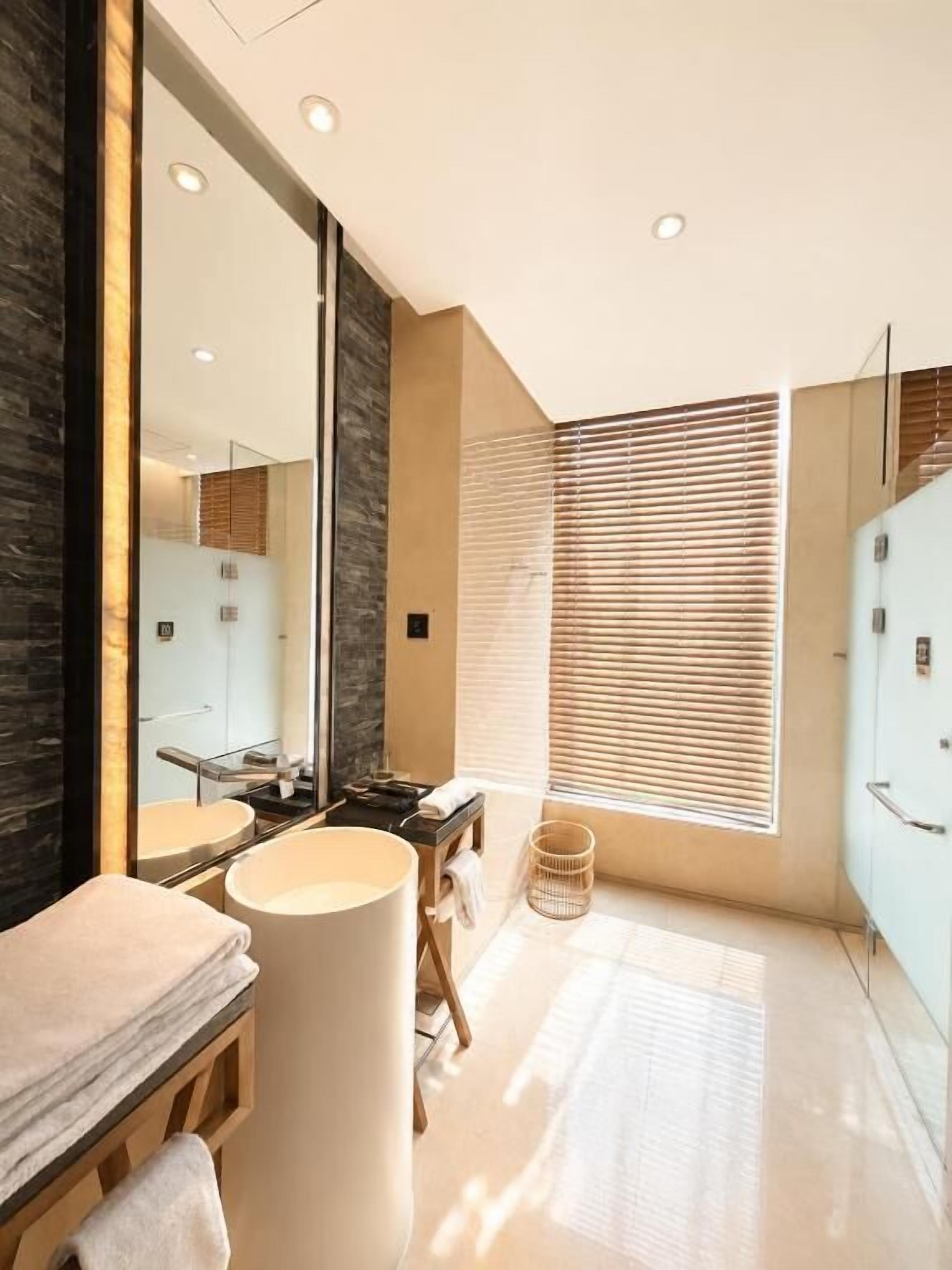 A modern bathroom with a large mirror, a sink, and a toilet.