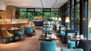 Een modern restaurant met een lange toonbank, meerdere tafels en stoelen.