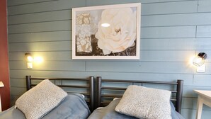 Een slaapkamer met twee bedden, een bloemrijk kunstwerk erboven en wandlampen.