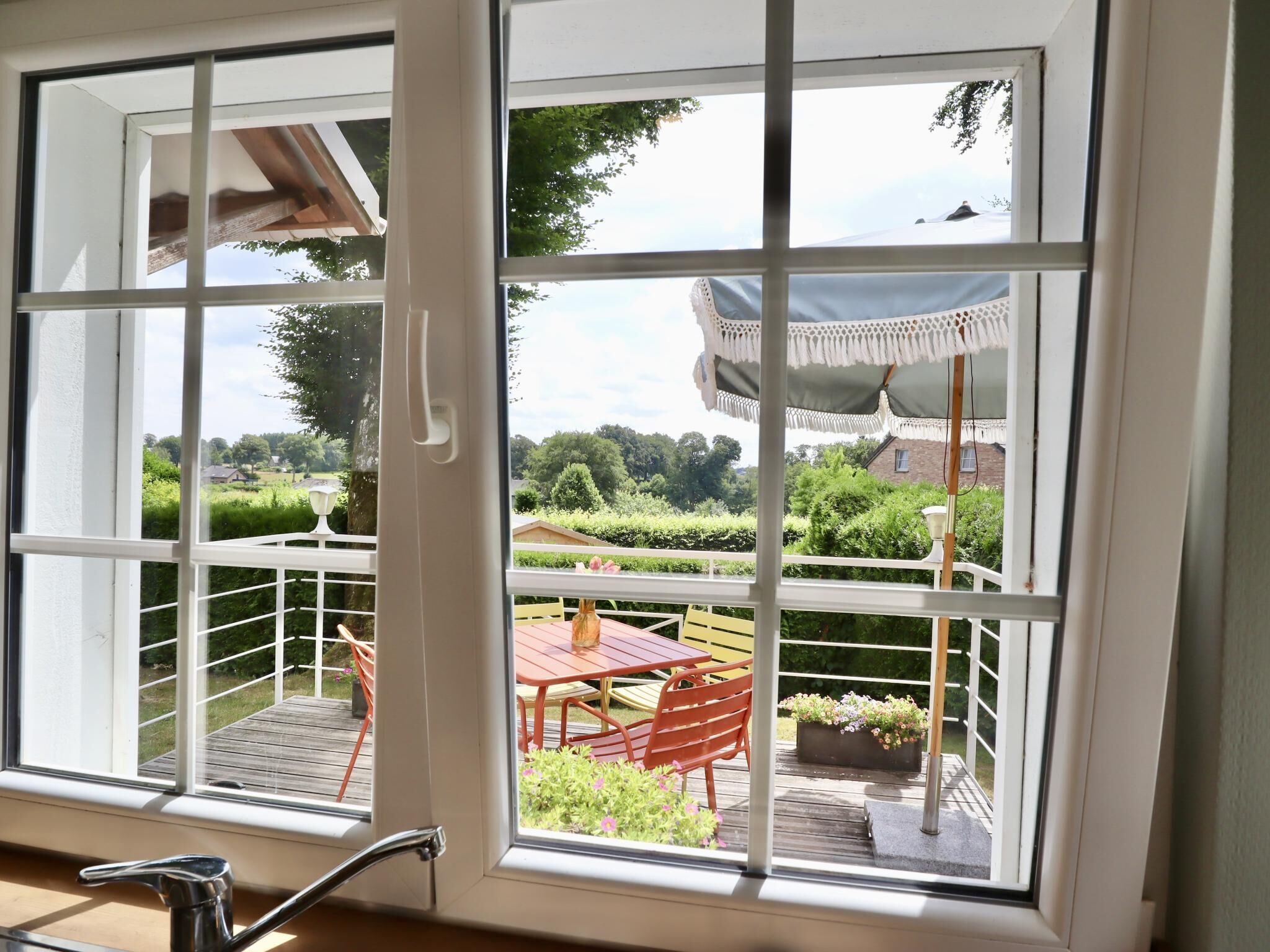 A room with a large window, a wooden deck, and a table with chairs.