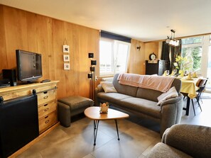 A furnished living room with a sofa, a coffee table, a television, and a cabinet. - Charming cottage near Lake Robertville (Robertville)