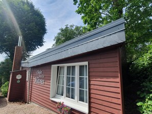 Un petit bâtiment à l’extérieur rouge, avec une fenêtre blanche et une cheminée.