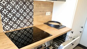 Een keuken met een zwart inductiekookveld, een inbouwoven en een vaatwasser.