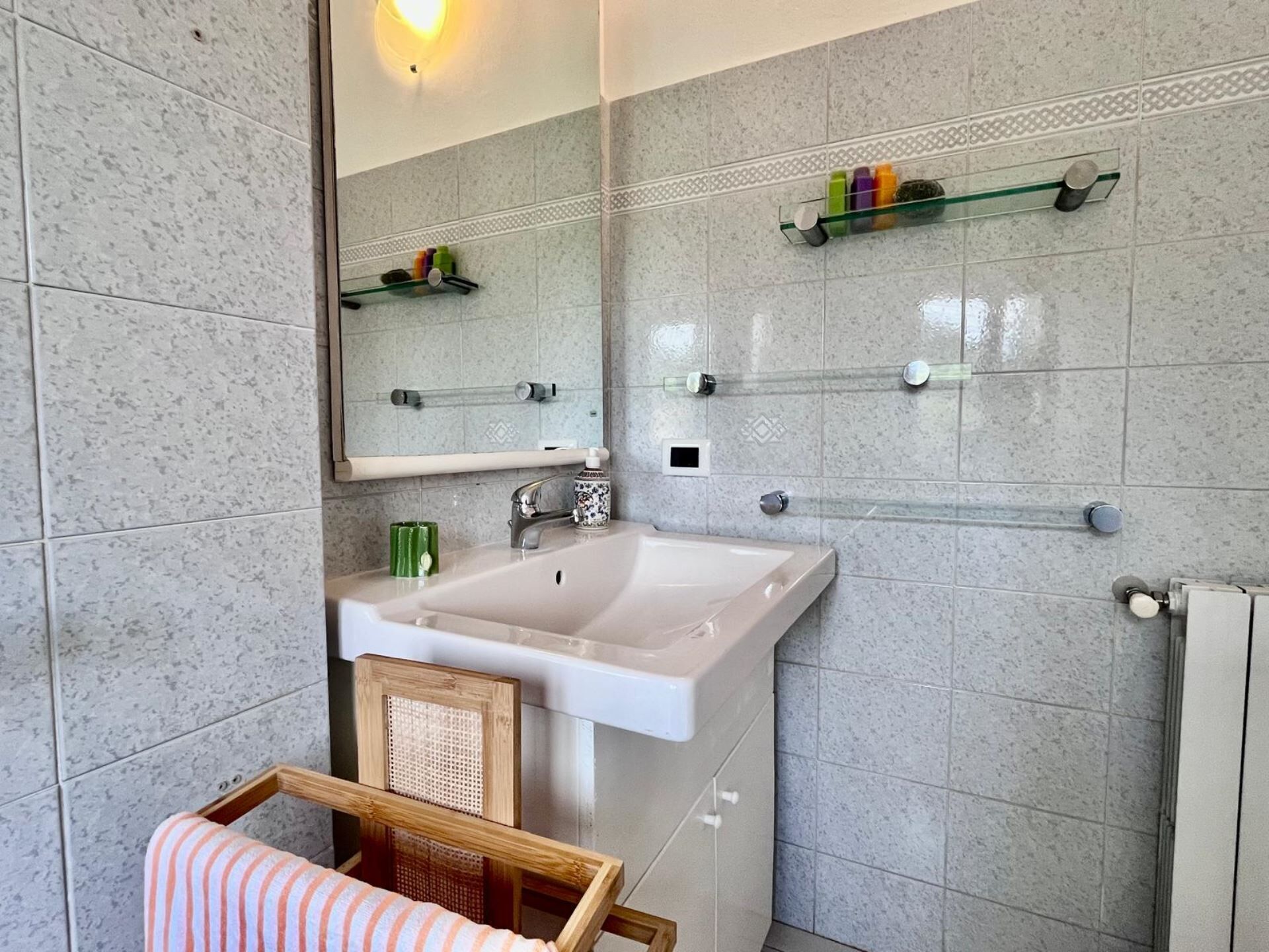 A bathroom with a white sink, a mirror, and a towel rack.