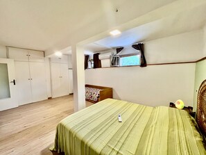 A bedroom with a bed, a wardrobe, a small table, and a window with curtains. - Villa Blu di Norsi: 100 steps to sea and peace (Capoliveri)