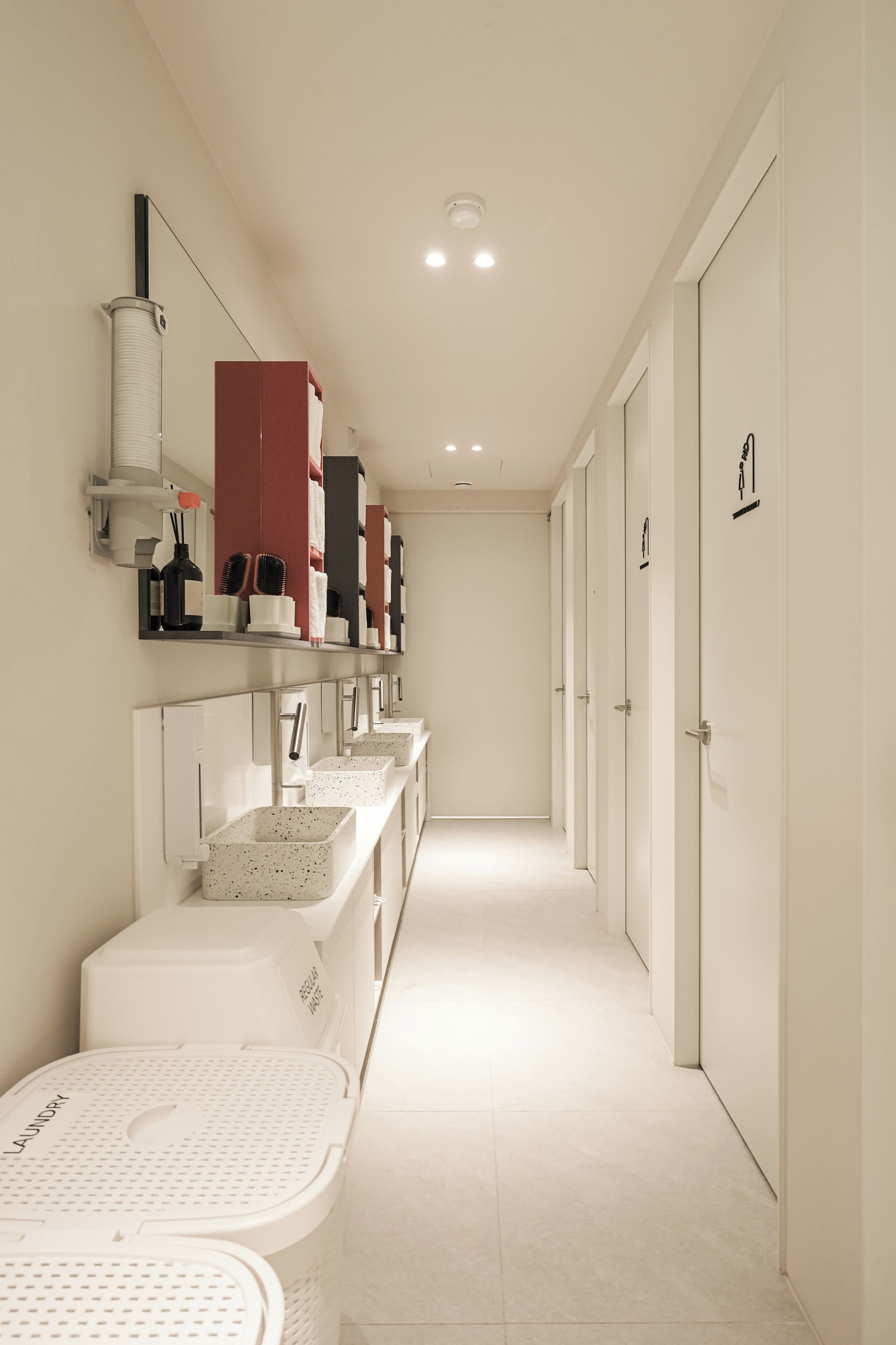 A clean, modern bathroom with multiple sinks, a drying station, and storage cabinets.