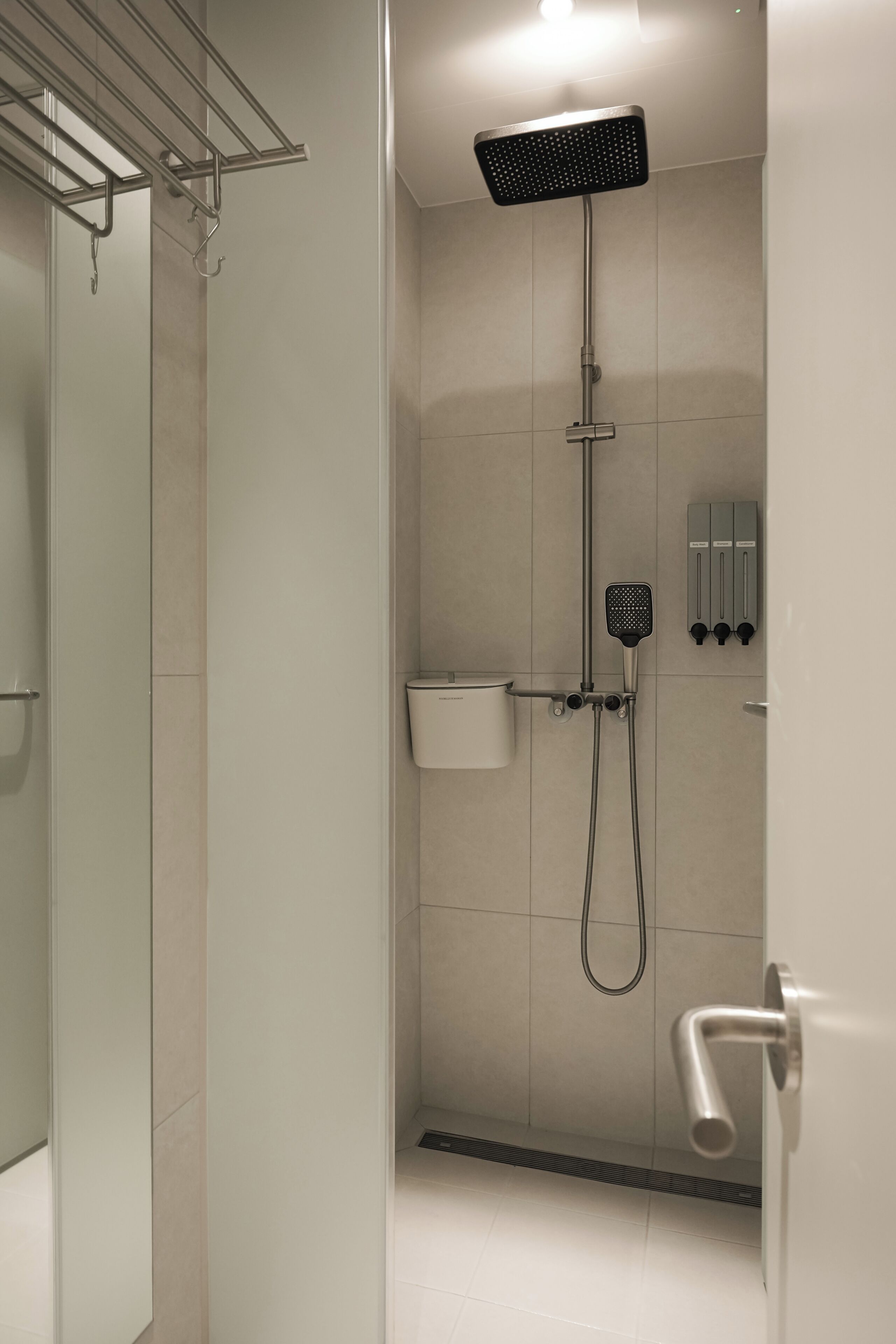 A modern shower with a handheld showerhead, a wall-mounted control panel, and a glass-enclosed shower area.