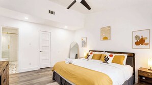 A bedroom with a bed, bedside table, and a door leading to a bathroom. - Cozy East Austin 3BR for 6, Near DT & Rodeo Austin! (Austin)
