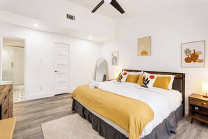 A bedroom with a bed, bedside table, and a door leading to a bathroom. - Cozy East Austin 3BR for 6, Near DT & Rodeo Austin! (Austin)