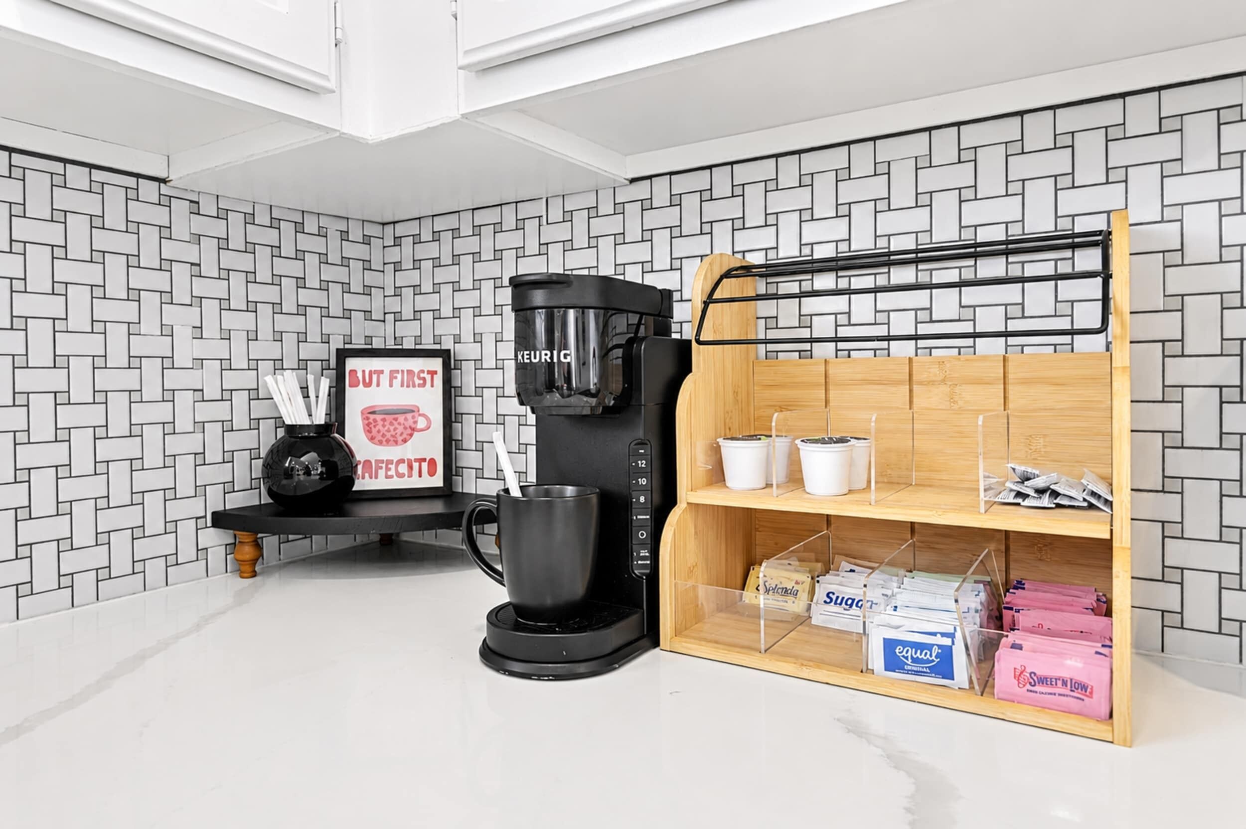 A modern kitchen with a coffee maker, a framed sign, and a wooden shelf with boxes.