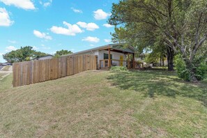 Une maison avec une clôture en bois, un porche couvert et une cour gazonnée.