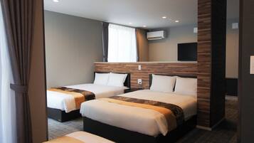 Quarto de hotel com duas camas, televisão de tela plana, ar condicionado e janela com cortinas.