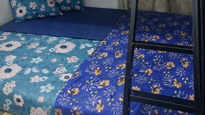 Un lit superposé composé d’un lit inférieur et d’un lit supérieur, tous deux dotés de draps à motifs floraux.