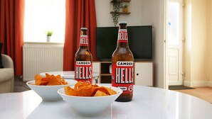 Dues ampolles de cervesa Camden Hells i dos plats de patates fregides sobre una taula blanca.