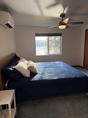 Une chambre à coucher avec un lit, un ventilateur de plafond, une fenêtre donnant sur un beau paysage et un appareil de climatisation.