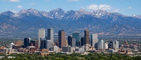 A cityscape with modern skyscrapers and a mountain range in the background.