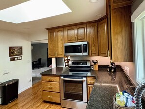 A modern kitchen with wooden cabinets, a stainless steel stove, and a microwave. - Welcome to Your Family's Ultimate Colorado Basecamp! (Arvada)