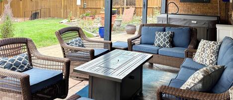 An outdoor patio area with wicker furniture, a table, and a barbecue grill.