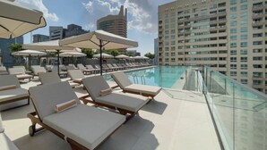 A rooftop pool area with lounge chairs and umbrellas, surrounded by high-rise buildings. - 1 Bed with City and Marina Views l near Mall (Dubai Marina)