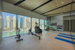 A gym with exercise equipment, a television, and a view of a cityscape. - 1 Bed City and Marina Views l Vida Residences (Dubai Marina)