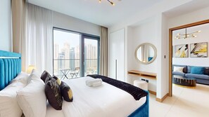 Une chambre d’hôtel dotée d’un grand lit, offrant une vue sur la ville, avec un balcon et un espace de vie moderne.