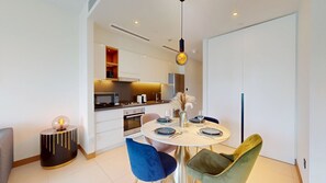 A modern kitchen with built-in appliances, a dining area with a round table and chairs, and a separate seating area with a sofa. - 1 Bed City and Marina Views l Vida Residences (Dubai Marina)